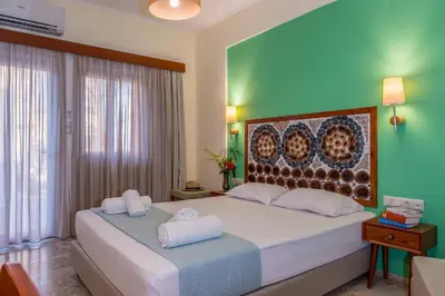 a bedroom with a large bed and a green wall at Aris Boutique Hotel in Palaiochóra