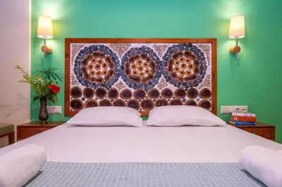 a bedroom with a white bed with a wooden headboard at Aris Boutique Hotel in Palaiochóra