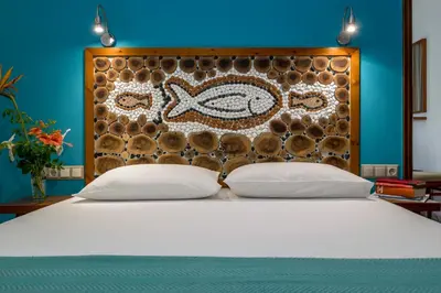 a bed with two pillows in front of a headboard at Aris Boutique Hotel in Palaiochóra