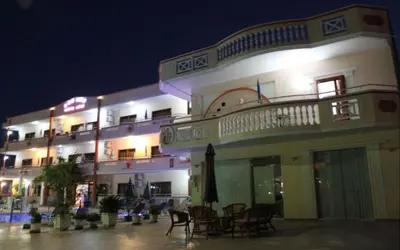 a building with chairs and tables in front of it at night at Sun City in Kato Daratso