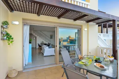 a patio with a table and chairs and a living room at PanDora maisonette with beautiful gardens and pool in Maleme