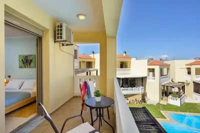 a room with a balcony with a bed and a table at PanDora maisonette with beautiful gardens and pool in Maleme