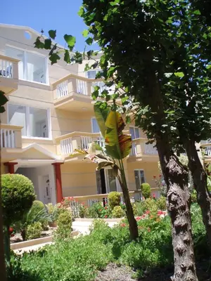 a large yellow building with white balconies and trees at Futura Hotel in Maleme