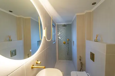 a bathroom with a white toilet and a round mirror at Futura Hotel in Maleme