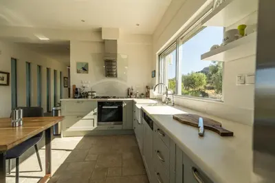 a kitchen with a sink and a large window at Villa Lucy by PosarelliVillas in Plataniás