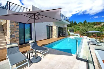 a house with a swimming pool and an umbrella at Villa Kallos by PosarelliVillas in Païdhokhórion
