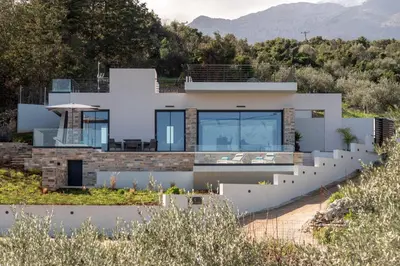 a house on the hill with mountains in the background at Villa Kallos by PosarelliVillas in Païdhokhórion