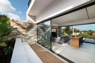 a glass extension of a house with a living room at Villa Kallos by PosarelliVillas in Païdhokhórion
