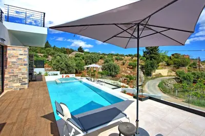 a patio with an umbrella and a swimming pool at Villa Kallos by PosarelliVillas in Païdhokhórion
