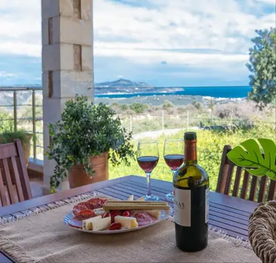 a table with a plate of food and two glasses of wine at Stone villa Halepa panoramic view, private pool,big garden & quiet in Néon Khoríon