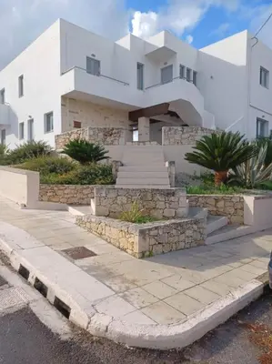 a large white building with stairs in front of it at Mini Villa Kalathas in Kalathas
