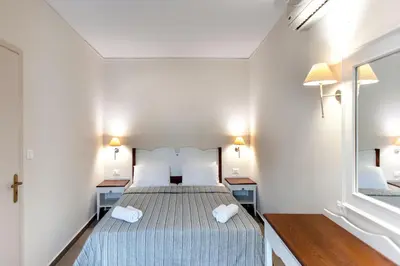 a bedroom with a bed and two tables and a mirror at Frideriki Studios & Apartments in Plataniás