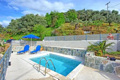a swimming pool with two chairs and an umbrella at Aretousa by PosarelliVillas in Dhrakóna