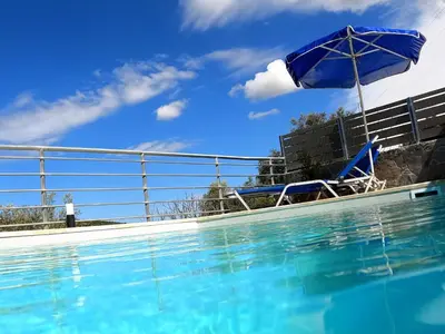 a swimming pool with a chair and an umbrella at Aretousa by PosarelliVillas in Dhrakóna