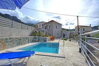 a swimming pool in front of a house at Aretousa by PosarelliVillas in Dhrakóna