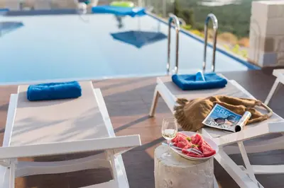 a table with a bowl of fruit and a glass of wine at Falasarna Luxury Villas I Private 