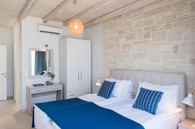 a bedroom with a blue and white bed and a stone wall at Falasarna Luxury Villas I Private 