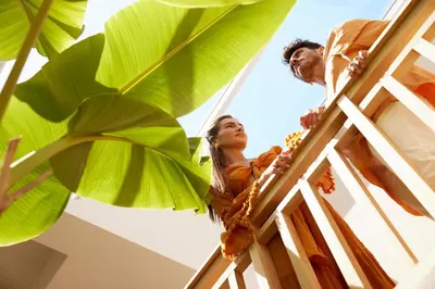 a man and a woman standing on a building with large green leaves at Asterion Suites & Spa - Designed for Adults in Gerani Chanion
