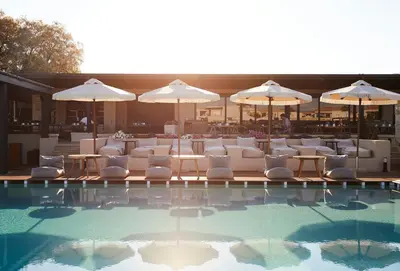 a pool with white lounge chairs and umbrellas at Asterion Suites & Spa - Designed for Adults in Gerani Chanion