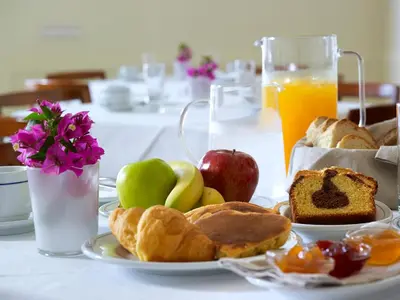 a table with a plate of breakfast foods and orange juice at Porto Veneziano Hotel in Chania Town