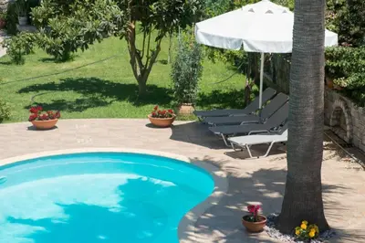 a swimming pool in a yard with a tree and a umbrella at Erodios Villas 2 in Ptinotrofíon