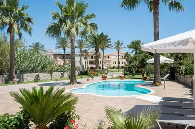 a swimming pool with palm trees and a building at Erodios Villas 2 in Ptinotrofíon
