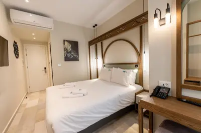 a bedroom with a large white bed and a telephone at El Greco Hotel in Chania Town