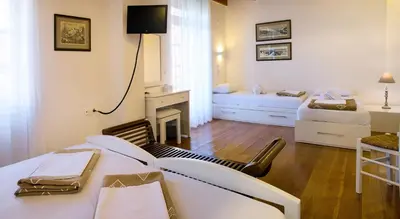 a room with two beds and a desk with a tv at Ontas Traditional Hotel in Chania Town