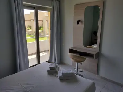 a bedroom with a bed with a mirror and a chair at Viglia Beach Apartments in Kissamos