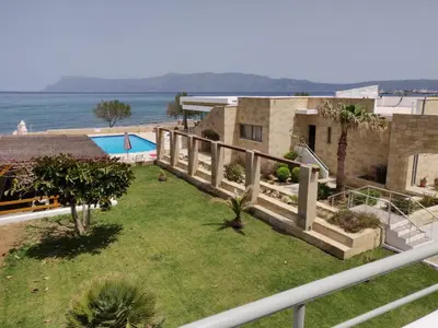 a house with a fence and a yard with a pool at Viglia Beach Apartments in Kissamos