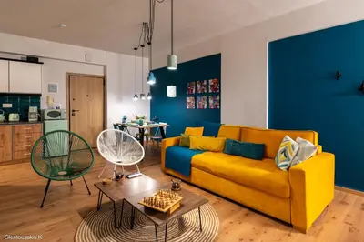 a living room with a yellow couch and a blue wall at Alsalos Sea View Apartment in Chania Town
