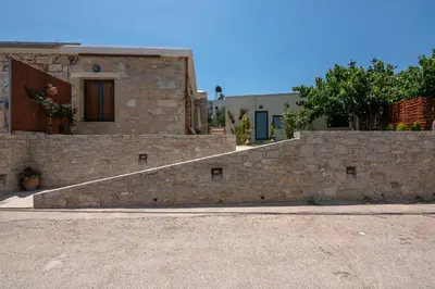 a stone wall with a staircase in front of a house at Cavos Luxury Apartments in Kissamos