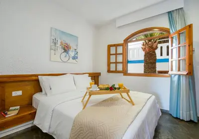 a bedroom with two beds and a table and a window at Folia Apartments Chania in Agia Marina Nea Kydonias