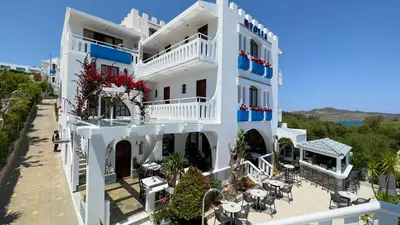 a white building with red flowers on the balconies at Folia Apartments Chania in Agia Marina Nea Kydonias