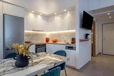 a kitchen with white cabinets and a table with chairs at Annet in Chania Town
