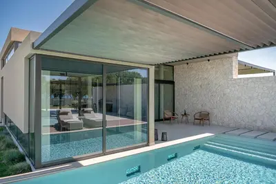 an external view of a house with a swimming pool at Pnoe Villas - Seafront Experience in Tavronitis