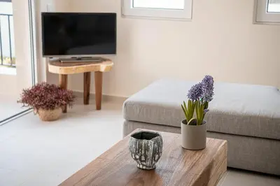 a living room with a couch and a table with purple flowers at Calmaliving Seaside apartments with pool in Gerani Chanion
