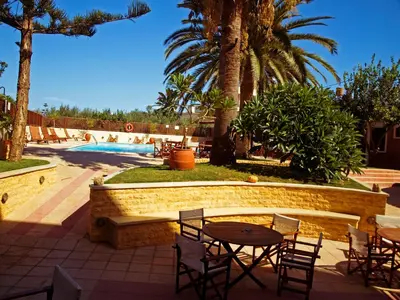 a patio with a table and chairs next to a pool at Kissamos Hotel in Kissamos