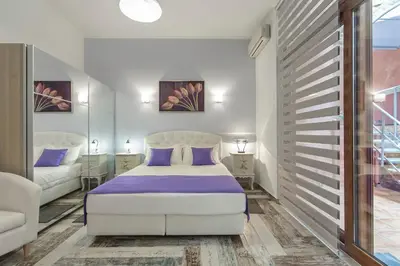 a bedroom with a white bed with purple sheets at KasteliSuites in Chania Town