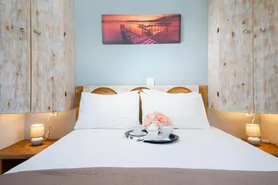 a bedroom with a bed with white sheets and two candles at Casa Maria 300 meters from the sea in Chania Town
