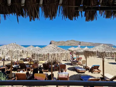 a beach with chairs and umbrellas and people on the sand at Claudia villa 2 in Agia Marina Nea Kydonias