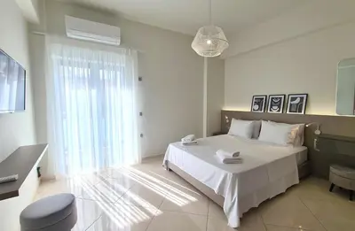 a bedroom with a white bed and a large window at Anna & Zampia central apts in Kissamos
