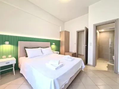 a bedroom with a large white bed and a bathroom at Anna & Zampia central apts in Kissamos