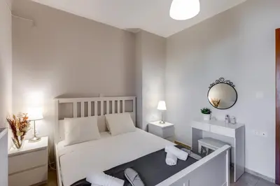 a bedroom with a white bed and a mirror at Stema City Apartment in Chania Town