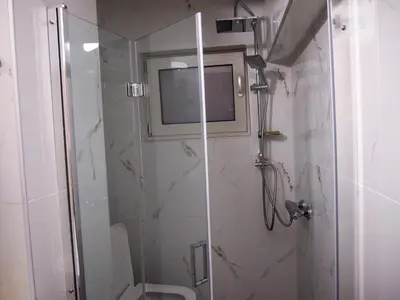 a bathroom with a shower with a toilet and a television at Charming apartment in Halepa! in Chania Town