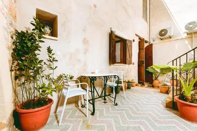 a patio with a table and chairs and potted plants at Bozzali Deluxe Hotel in Chania Town