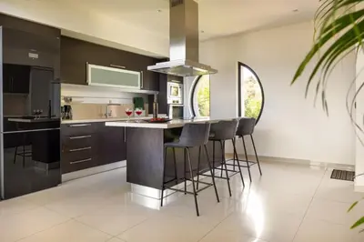 a kitchen with black cabinets and bar stools at SeaSilia Luxury Villa in Korakiaí