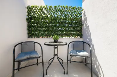 two chairs and a table in front of a green hedge at 2 bd downtown home with private parking 400 meters walk to the beach in Chania Town