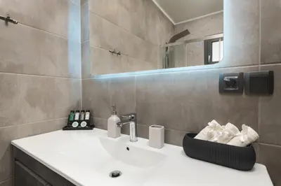 a bathroom with a white sink and a mirror at 2 bd downtown home with private parking 400 meters walk to the beach in Chania Town