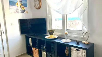a blue cabinet with a television and a window at D&R Sunshine Apartment in Agia Marina Nea Kydonias